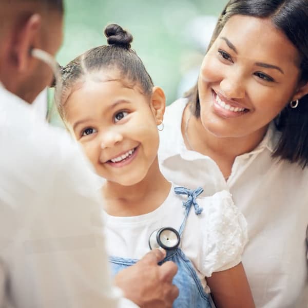 Mother holds daughter talking to doctor