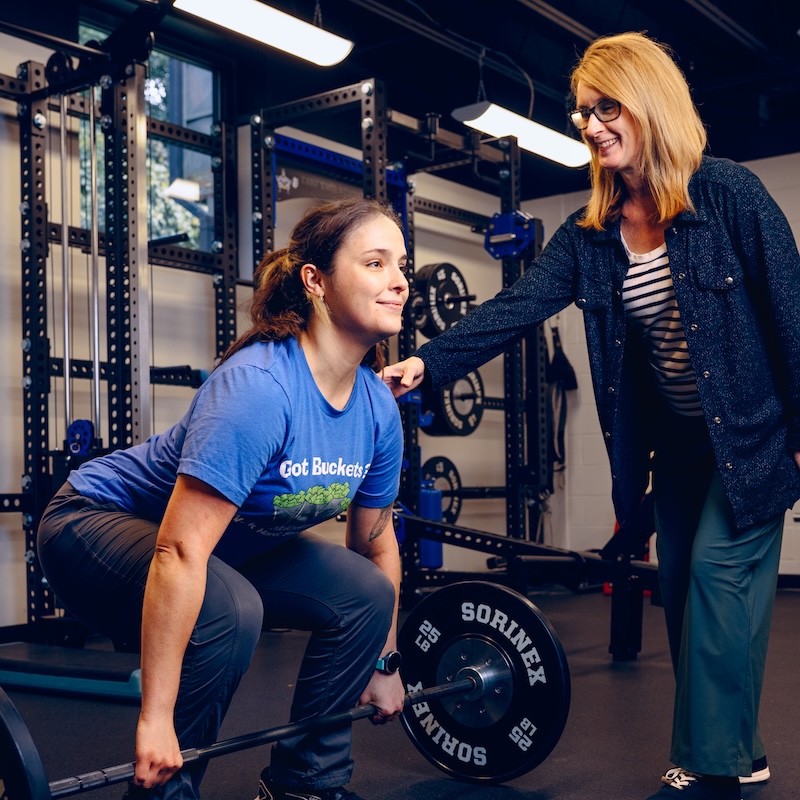 Trainer works with McKee coworker on deadlift form.